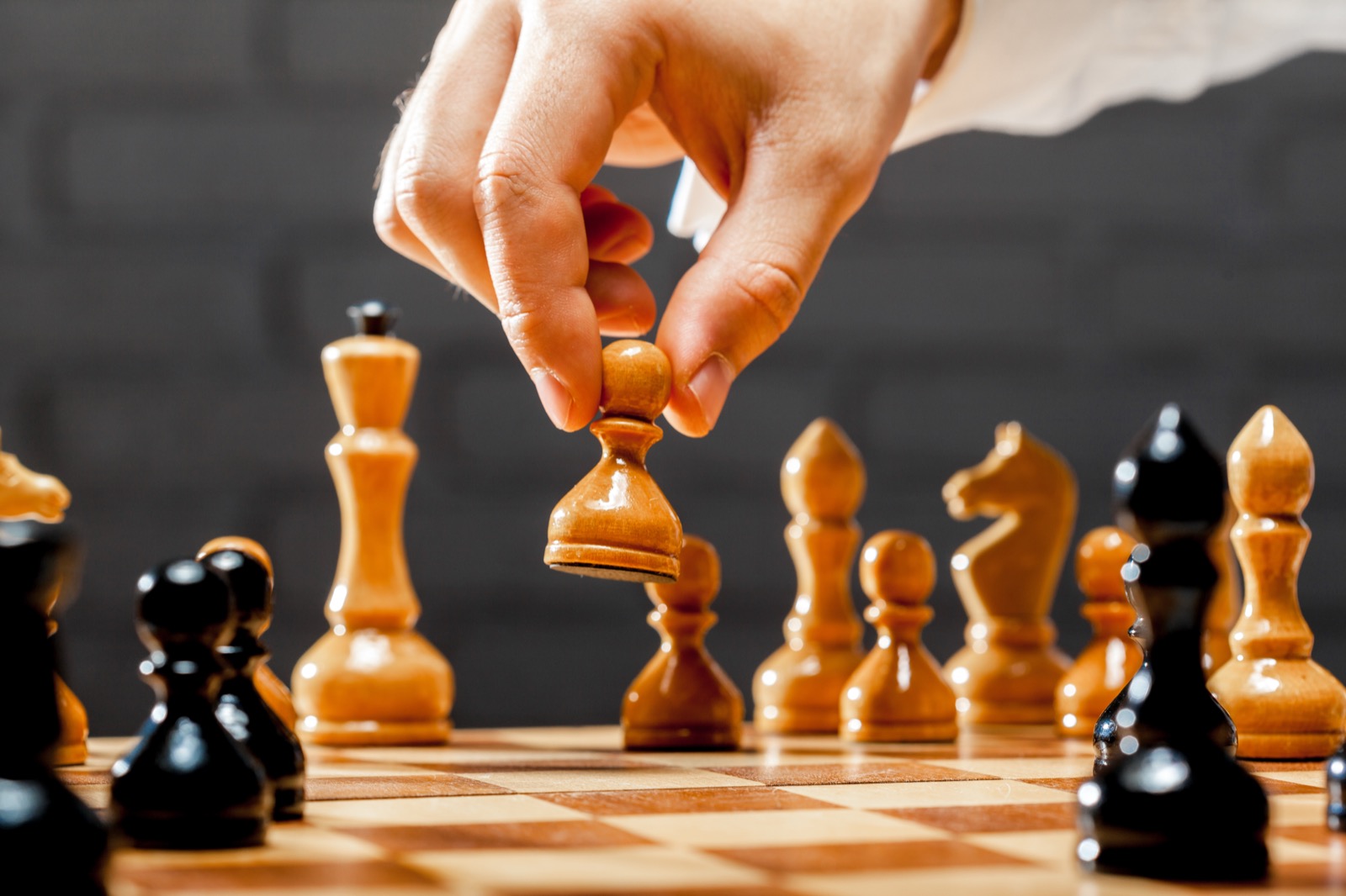 A hand moving a chess pawn on a board, a deliberate move made before the game is decided