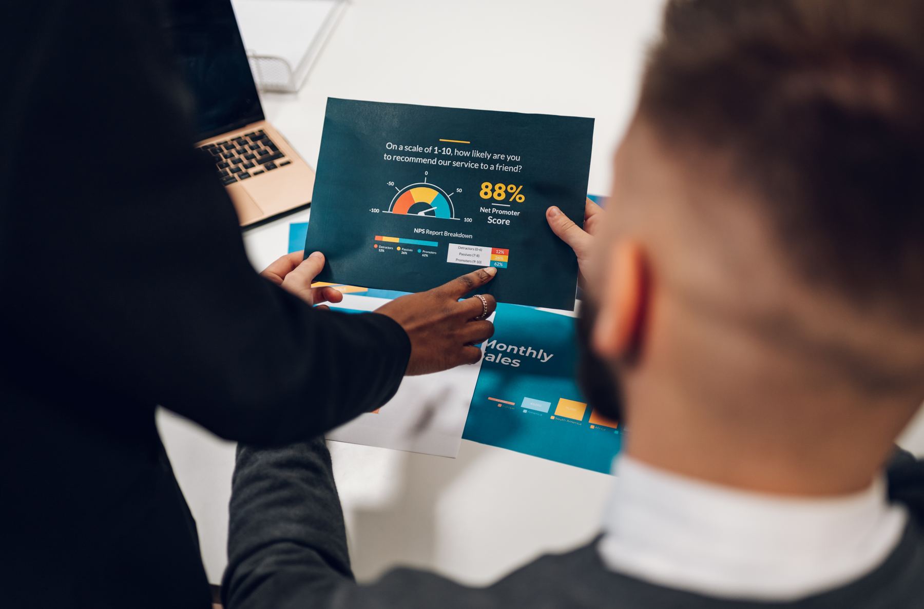 Two people reviewing a printed report page showing a Net Promoter Score chart