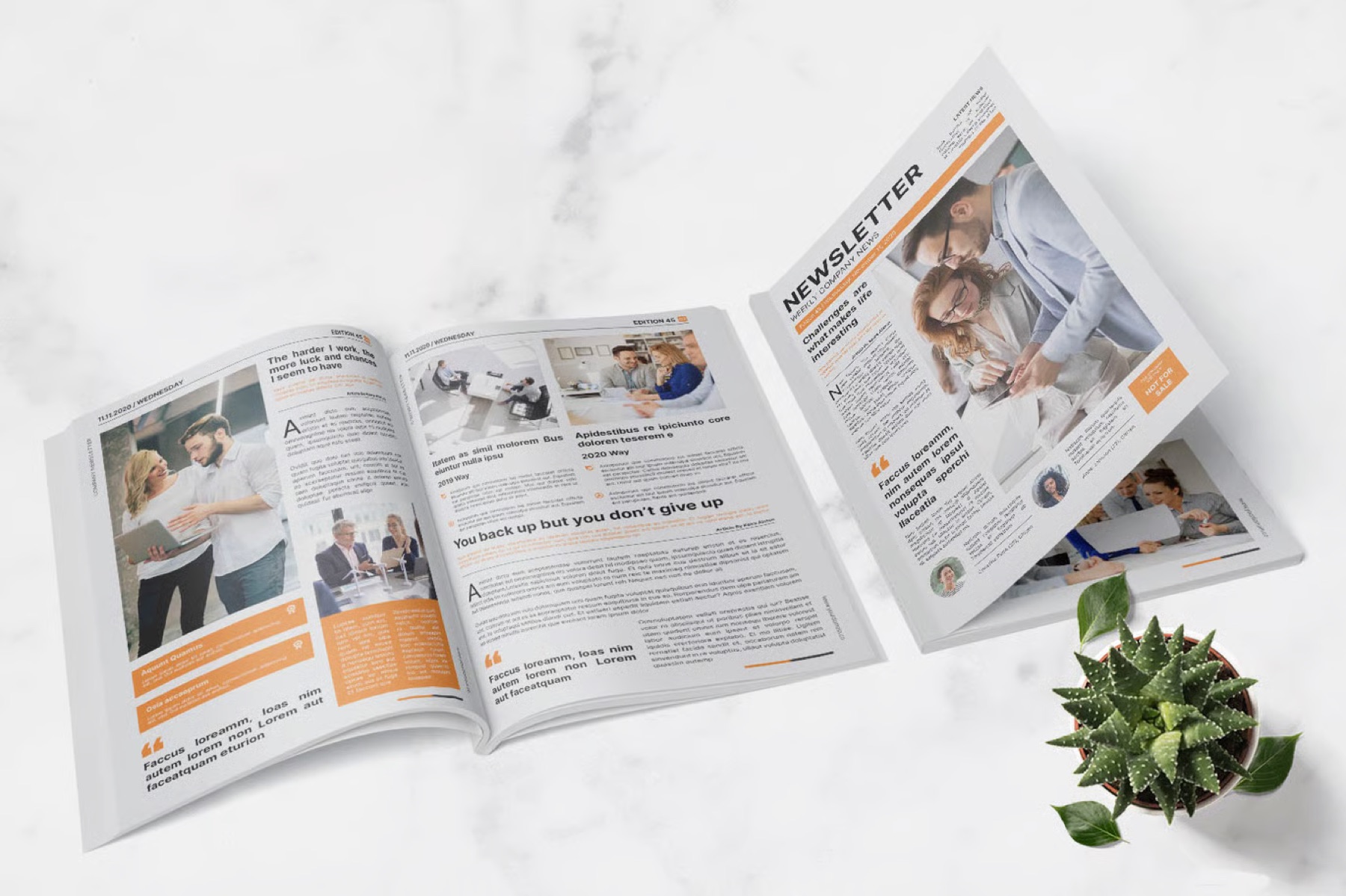A newsletter design mockup open on a marble surface, showing the cover and an inside spread layout